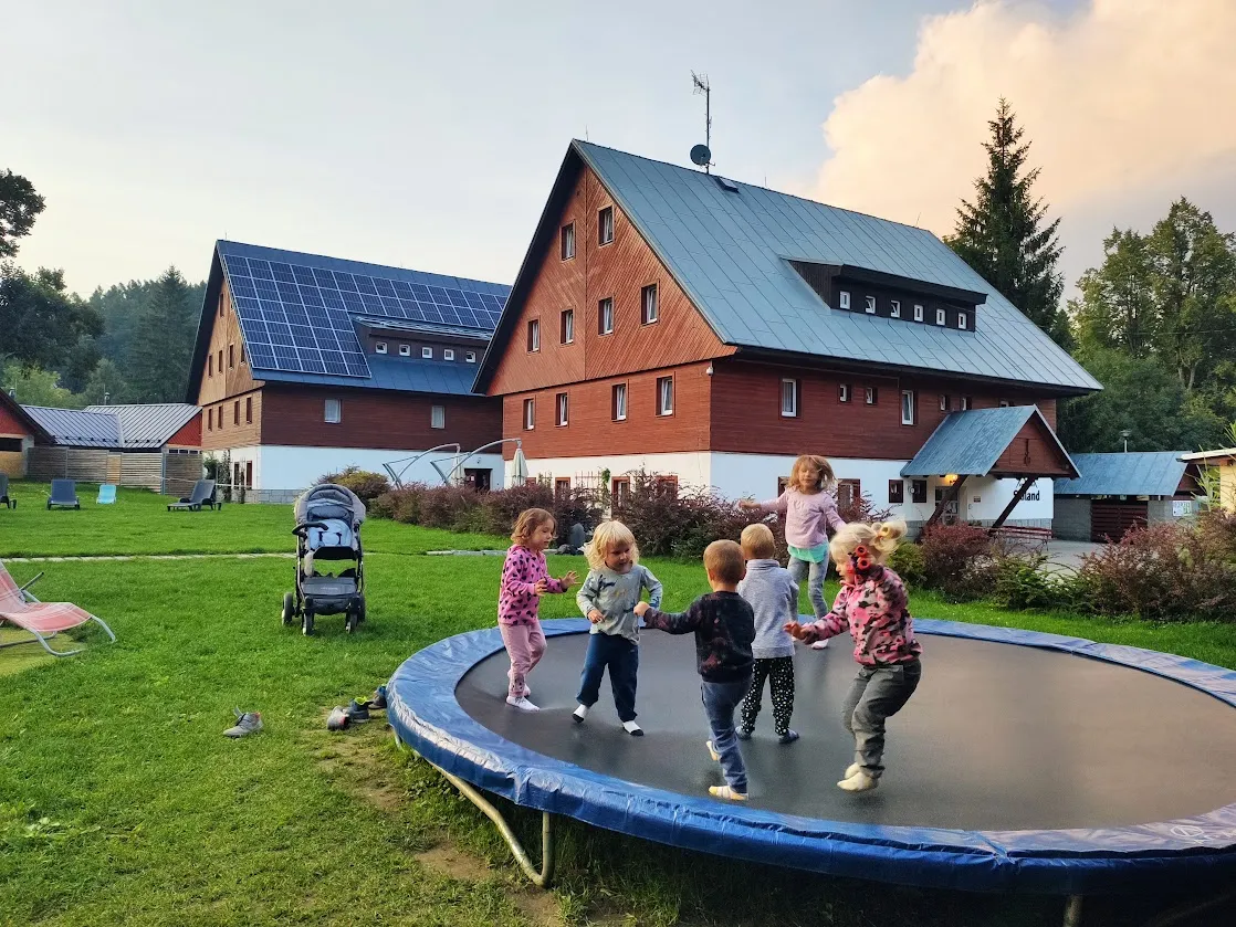 Skiland Ostružná s dětmi – zázemí hotelu v Jeseníkách Děti skáčou na trampolíně na zahradě před hotelem Skiland Ostružná v Jeseníkách.