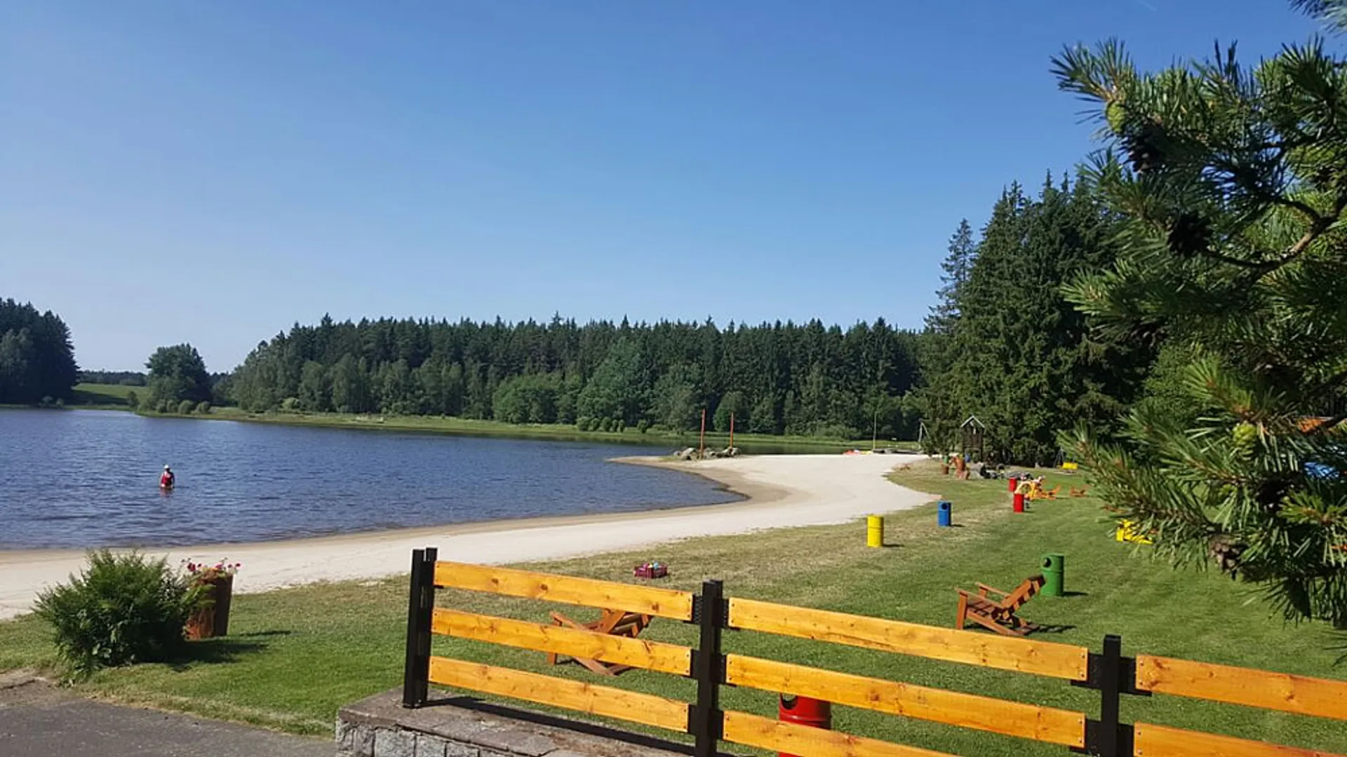Přírodní koupaliště Lido u Mariánských Lázní s písčitou pláží a lesem v okolí.