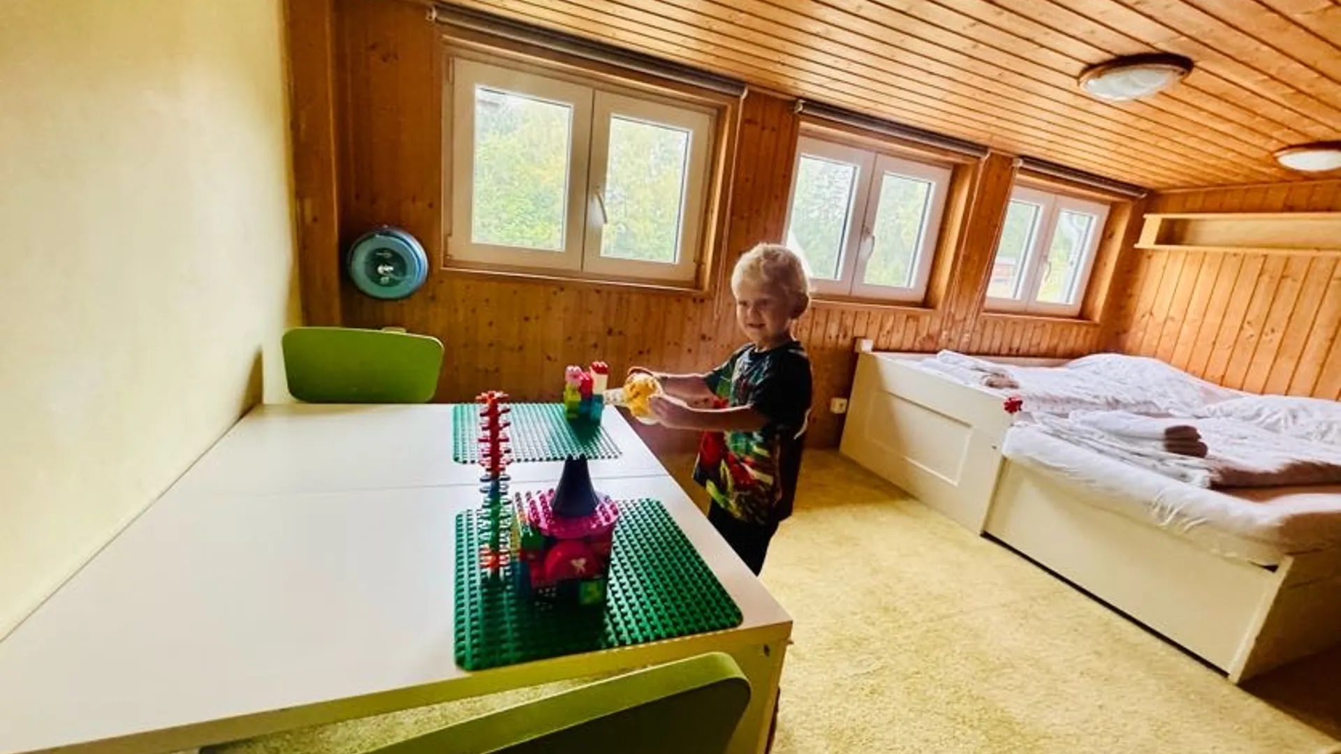 Rodinné ubytování v Hotelu Peklo v Josefově Dole Malé dítě si hraje v rodinném pokoji Hotelu Peklo s postelí a dětským stolkem.