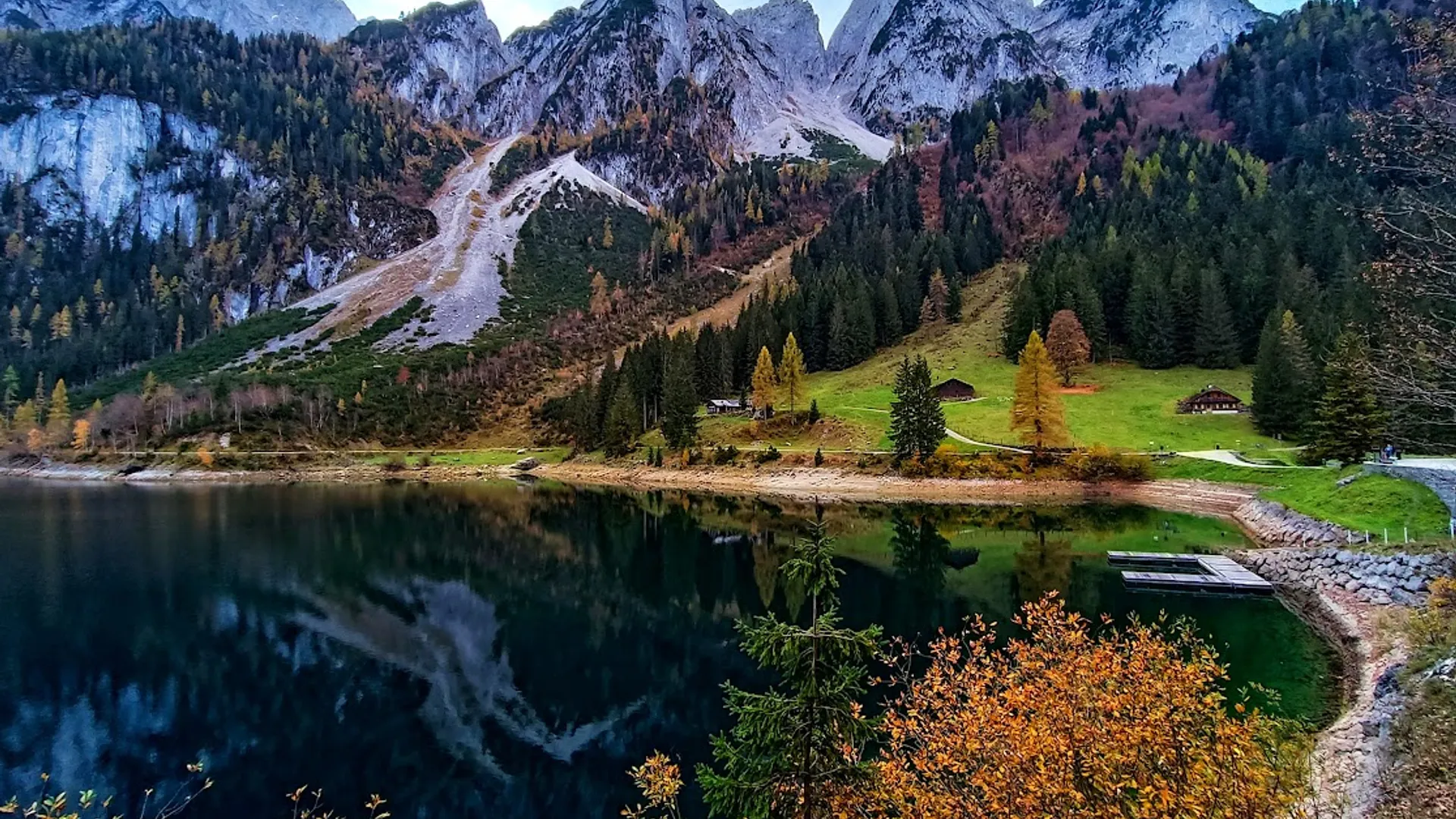 Podzimní jezero u Hallstattu Jezero pod horskými svahy s lesy v podzimních barvách.