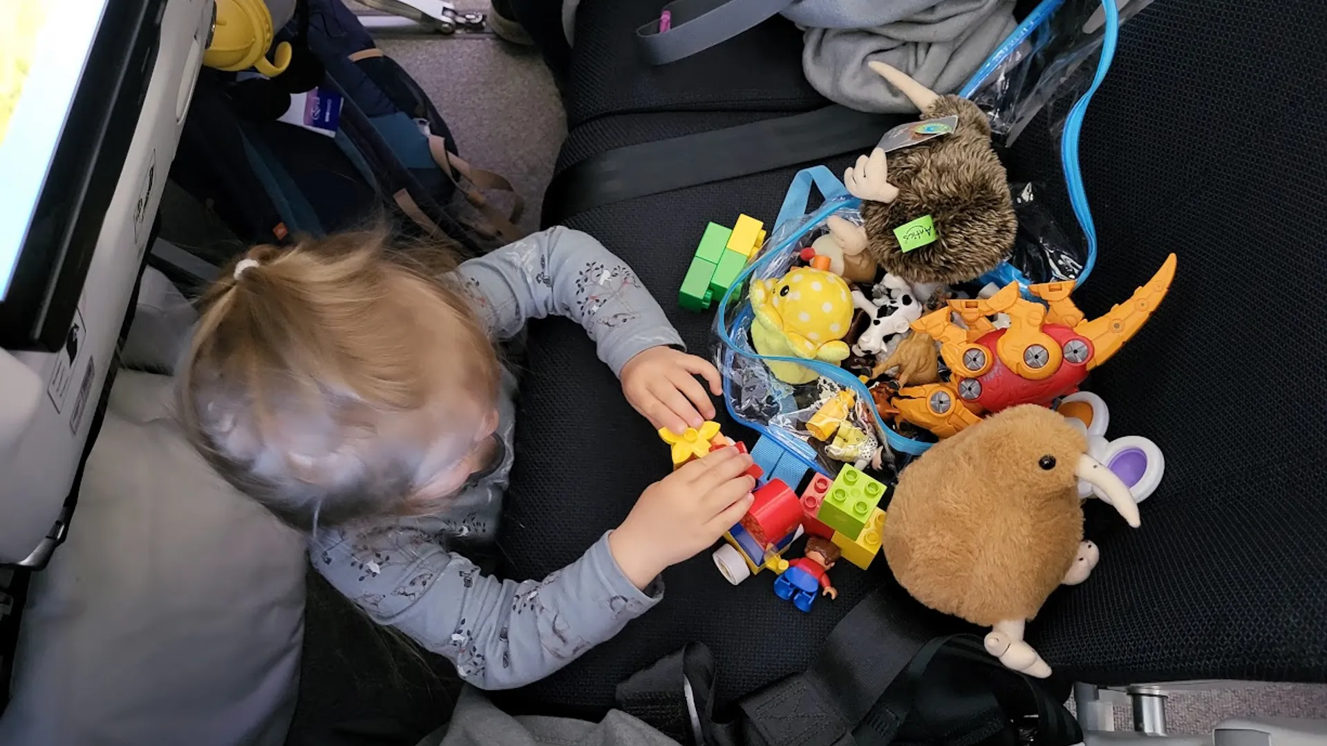 Co přibalit dětem na cestu pro zabavení malé dítě si hraje s figurkami a dalšími hračkami na sedadle během cesty